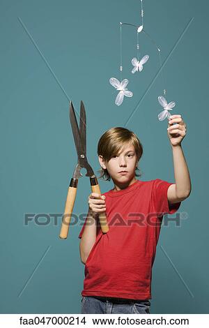 Boy standing below butterfly mobile, holding hedge clippers View Large Photo Image Picture - Boy standing below butterfly mobile, holding hedge clippers. Fotosearch