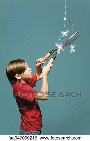 Boy using hedge clippers to cut down butterfly mobile View Large Photo Image Stock Photography - Boy using hedge clippers to cut down butterfly mobile. Fotosearch