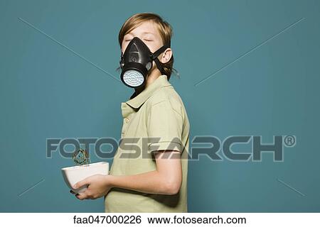 Boy wearing gas mask, holding wilted potted plant View Large Photo Image Stock Photograph - Boy wearing gas mask, holding wilted potted plant. Fotosearch