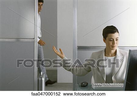Businesswoman sitting at desk working, motioning for man to enter office View Large Photo Image Stock Image - Businesswoman sitting at desk working, motioning for man to enter office. Fotosearch
