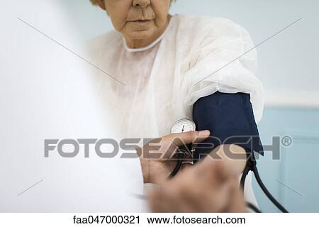 Stock Image - Doctor checking patient's blood pressure, cropped. Fotosearch