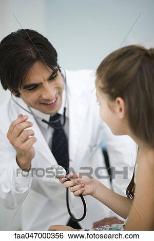 Stock Photograph - Doctor showing little girl how to use stethoscope. Fotosearch