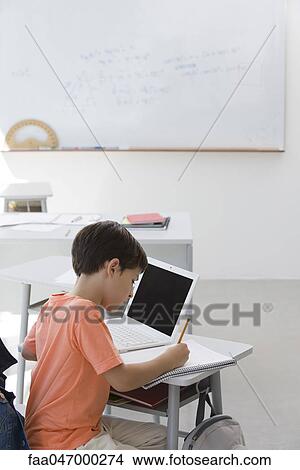 Elementary school student busy doing assignment in classroom View Large Photo Image Picture - Elementary school student busy doing assignment in classroom. Fotosearch