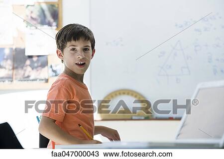 Stock Image - Elementary school student in classroom, looking over shoulder. Fotosearch