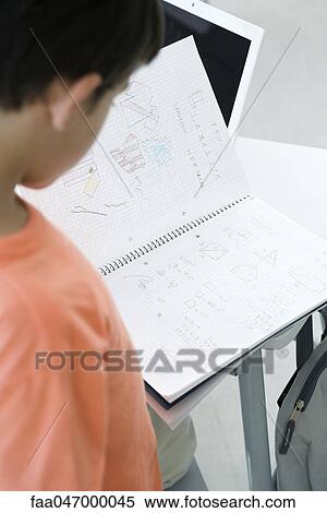 Stock Photography - Elementary school student looking through notebook. Fotosearch