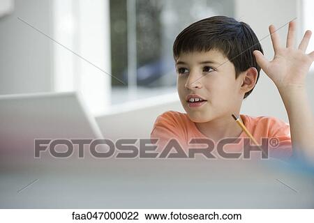 Stock Image - Elementary school student raising hand in class. Fotosearch