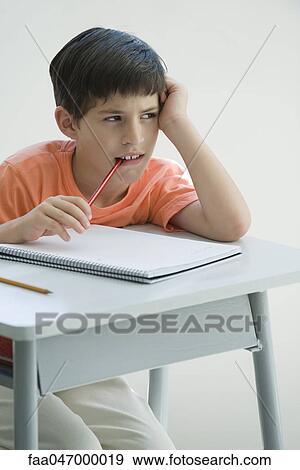 Elementary School Student Sitting At Desk Leaning On Elbow