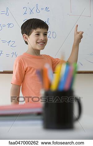 Stock Image - Elementary school student standing in front of class, pointing at whiteboard. Fotosearch