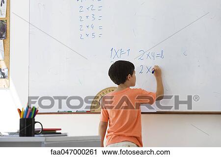 Stock Image - Elementary school student working math equations on whiteboard. Fotosearch