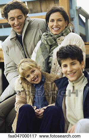 Stock Photo - Family sitting together on deck, portrait. Fotosearch
