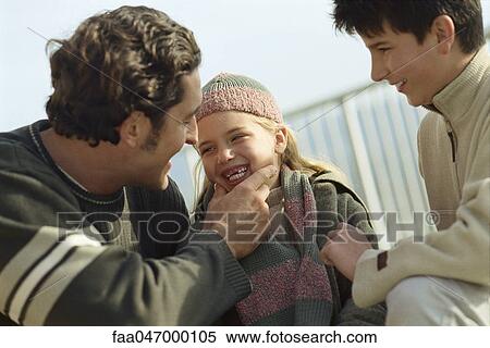 Stock Photography - Family together outdoors, father laughing at daughter's missing teeth. Fotosearch