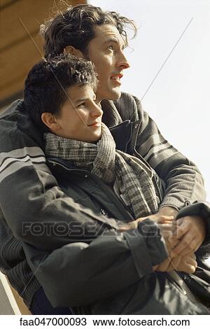 Stock Image - Father and son together outdoors, both looking away, portrait. Fotosearch