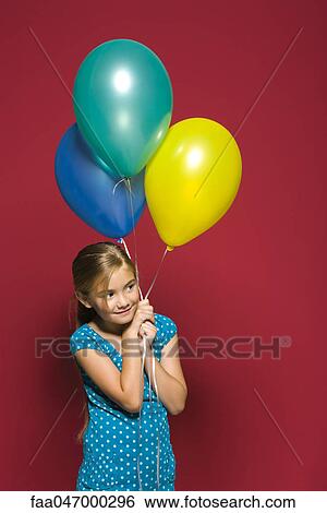 Stock Photograph - Girl holding balloons, looking away, smiling. Fotosearch