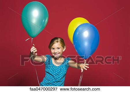 Stock Photo - Girl standing with balloons, smiling, portrait. Fotosearch