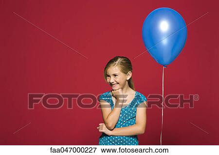 Girl with hand under chin, balloon suspended behind her View Large Photo Image Stock Photo - Girl with hand under chin, balloon suspended behind her. Fotosearch