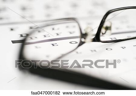 Stock Image - Glasses on eye chart. Fotosearch