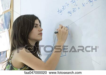 Stock Image - High school student writing equation on whiteboard. Fotosearch