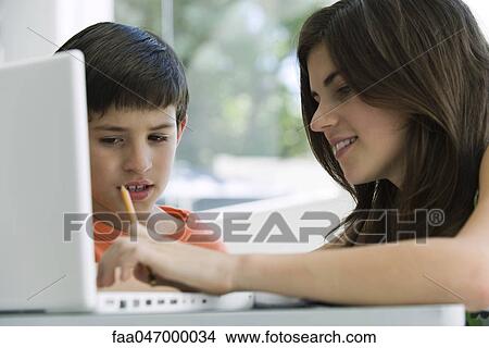 Picture - Little boy watching older sister use laptop computer. Fotosearch
