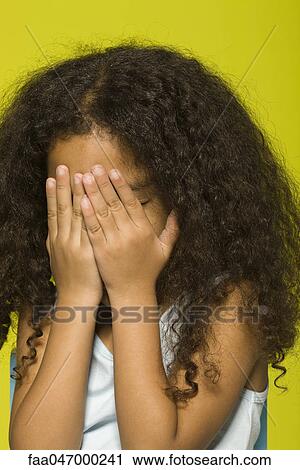Stock Image - Little girl covering face with hands. Fotosearch