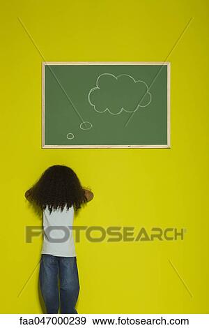 Stock Photo - Little girl facing wall, thought bubble on chalkboard. Fotosearch