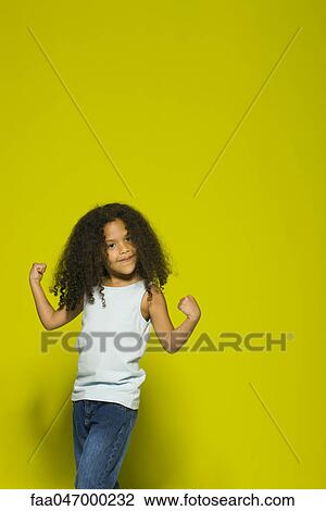 Stock Image - Little girl flexing muscles, portrait. Fotosearch