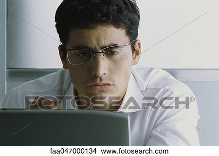 Picture - Man using computer, frowning. Fotosearch