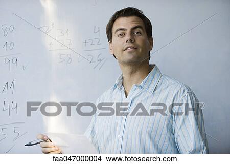 Picture - Math teacher in front of whiteboard, looking expectantly. Fotosearch