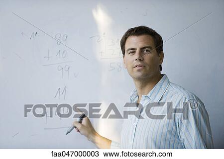 Stock Image - Math teacher pointing to equation on whiteboard. Fotosearch