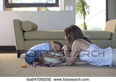 Mother and young son together in living room playing, boy hugging stuffed toy View Large Photo Image Stock Image - Mother and young son together in living room playing, boy hugging stuffed toy. Fotosearch