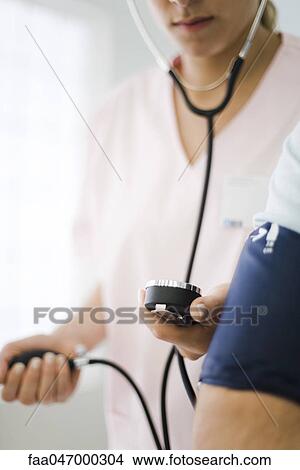 Picture - Nurse checking patient's blood pressure, cropped. Fotosearch