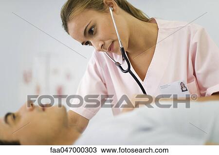 Stock Image - Nurse listening to male patient's chest with stethoscope. Fotosearch