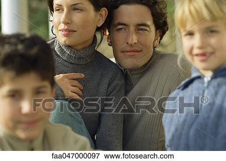 Stock Photo - Parents looking away, smiling, children in foreground. Fotosearch