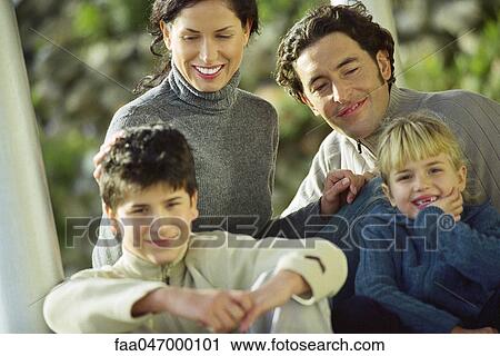 Stock Image - Parents sitting outdoors with their two children. Fotosearch