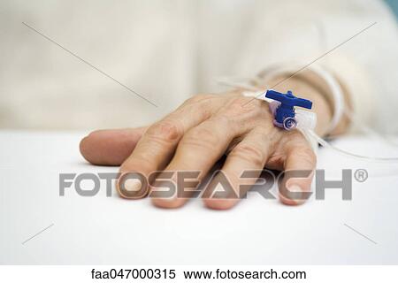 Stock Photography - Patient's hand with IV drip. Fotosearch