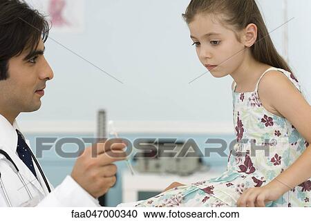Stock Image - Pediatrician explaining syringe to little girl. Fotosearch