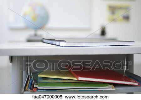 Stock Photography - School desk containing stack of books, notebooks. Fotosearch
