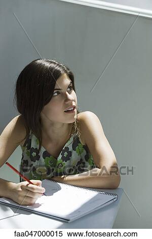 Stock Photography - Teenage girl with pen and notebook, looking over shoulder out window. Fotosearch