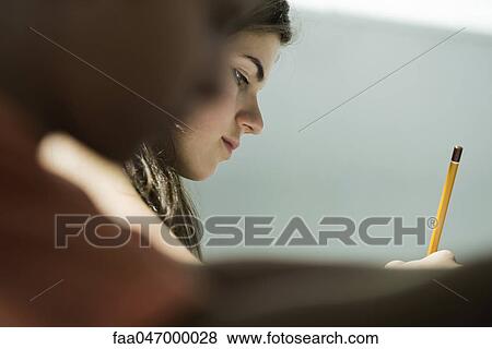 Teenage girl writing in class, side view View Large Photo Image Stock Photo - Teenage girl writing in class, side view. Fotosearch