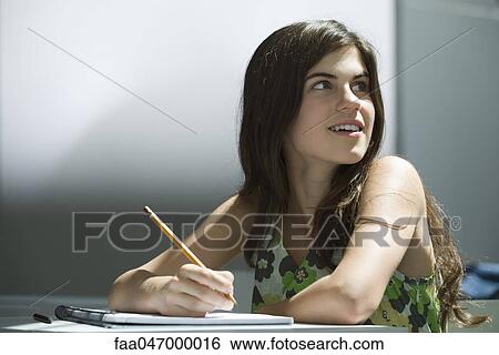 Teenage girl writing in notebook, dreamily looking away View Large Photo Image Stock Photograph - Teenage girl writing in notebook, dreamily looking away. Fotosearch