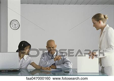 Stock Image - Three business colleagues collaborating in office. Fotosearch
