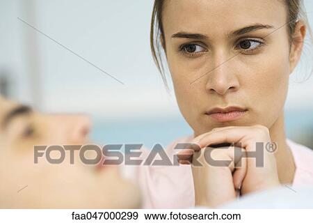 Stock Photo - Woman watching sick patient, hands clasped under chin. Fotosearch