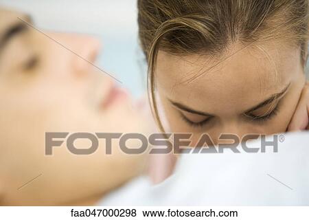 Stock Photo - Woman with head down, man asleep in foreground. Fotosearch