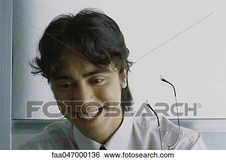 Young businessman laughing, holding glasses View Large Photo Image Stock Photograph - Young businessman laughing, holding glasses. Fotosearch