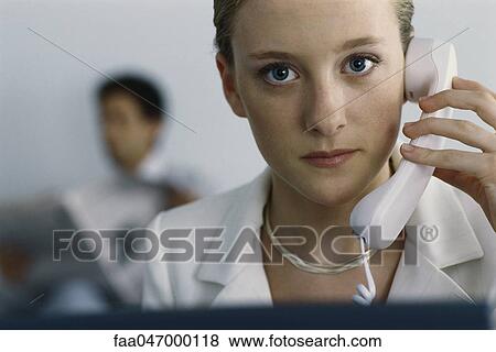 Young businesswoman holding phone to ear, looking at camera View Large Photo Image Stock Photo - Young businesswoman holding phone to ear, looking at camera. Fotosearch