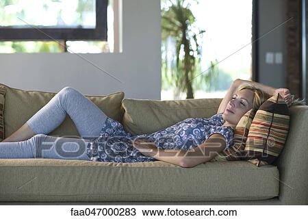 Young woman reclining on sofa with eyes closed View Large Photo Image Stock Image - Young woman reclining on sofa with eyes closed. Fotosearch
