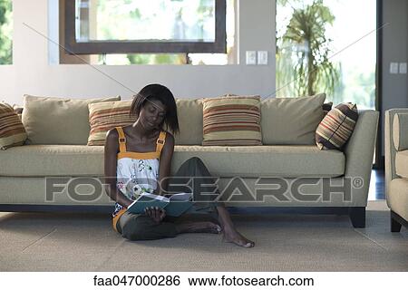 Young woman sitting on living room floor reading book View Large Photo Image Stock Photograph - Young woman sitting on living room floor reading book. Fotosearch
