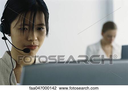 Young woman wearing headset and using computer View Large Photo Image Stock Image - Young woman wearing headset and using computer. Fotosearch