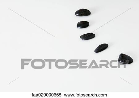 Stock Photography - Black pebbles lined up in a curve, close-up. Fotosearch