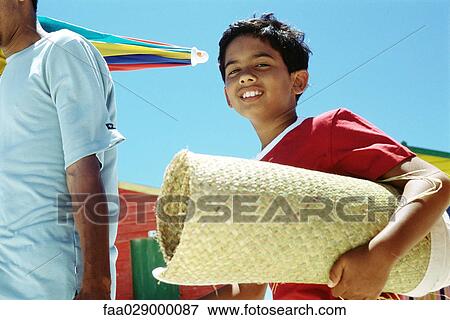 Boy carrying rolled up beach mat, smiling at camera View Large Photo Image Stock Photo - Boy carrying rolled up beach mat, smiling at camera. Fotosearch