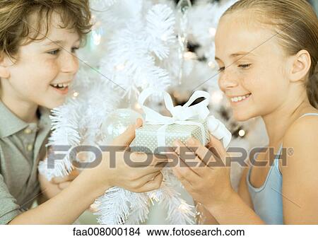 Boy handing girl christmas gift View Large Photo Image Picture - Boy handing girl christmas gift. Fotosearch